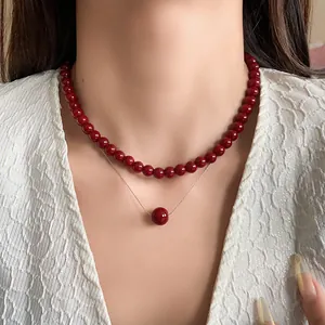 Close-up of minimalist Anchora red beaded necklace and pendant on model