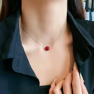 Close-up view of a minimalist necklace featuring a single red pearl on a fine silver chain