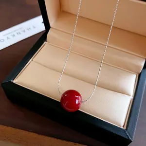 Close-up of a minimalist red pearl pendant necklace displayed in a jewelry box