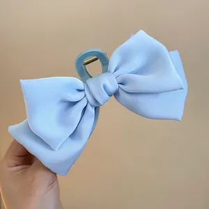 Detailaufnahme einer eleganten hellblauen Stoffschleifen-Haarklammer in der Hand