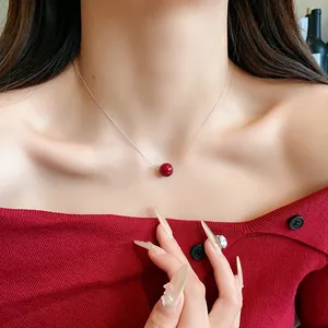 Close-up of elegant minimalist red pearl necklace on thin silver chain worn by woman