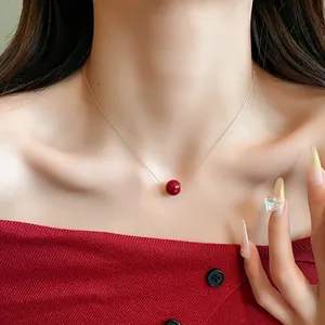Detailed view of an elegant red pearl necklace worn on a woman's neck for a chic look
