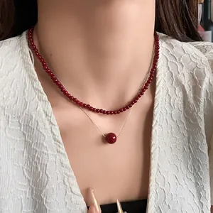 Elegant double-layered red bead necklace on model with a white textured blouse