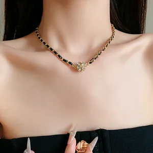 Gros plan détaillé d'un collier chaîne en cuir vintage avec une perle en strass brillante.