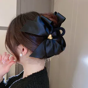 Detailaufnahme einer eleganten schwarzen Satin-Schleife-Haarklammer mit goldenem Herz