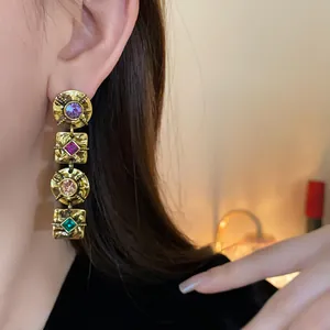 Close-up view of vintage gold drop earrings with multicolor rhinestones on model