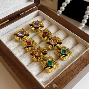 Detailed view of vintage gold earrings with multi-colored square and round gemstones