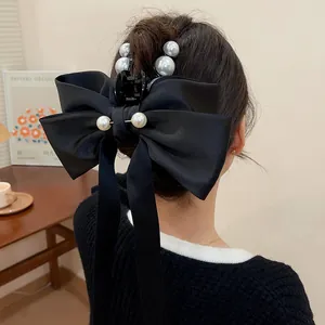 Detailansicht einer eleganten schwarzen Haarklammer mit Satinschleife und weißen Perlen