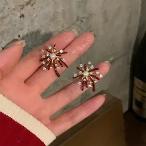 Macro view of French style red firework shaped earrings with zircon and pearl details