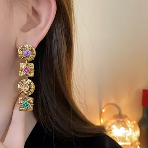 Close-up of vintage gold-toned earrings with colorful square and round rhinestones