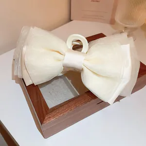 Nahaufnahme einer eleganten, cremefarbenen Haarklammer mit geschichteter Schleife.
