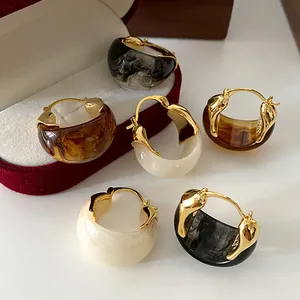 Detail view of vintage U-shaped gold hoop earrings with ink marble resin pattern