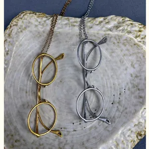 Vintage metal eyeglass pendant necklaces in gold and silver tones on a ceramic plate