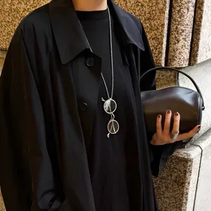 Detailed view of a silver minimalist necklace with a vintage round glasses pendant