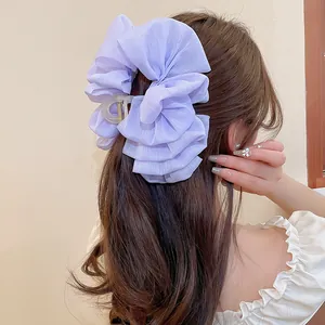 Detailansicht einer großen violetten Haarklammer mit Rüschenschleife auf braunem Haar
