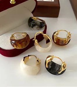 Detailed macro shot of marbled U-shaped hoop earrings in amber, white and black smoke
