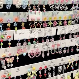 Vista dettagliata di vari orecchini colorati in stile dolce con forme di cuori e fiori.
