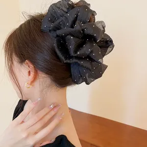 Detailansicht einer großen schwarzen Haarklammer mit Punkten im Haar einer eleganten Frau.