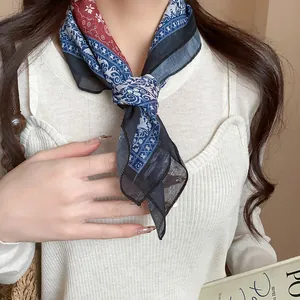 Close-up detail showing a retro printed floral square scarf tied around a woman's neck