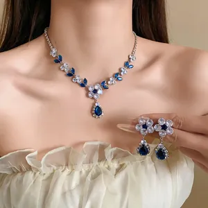Elegante set collana fiori in zircone con pendenti a goccia blu indossato da modella