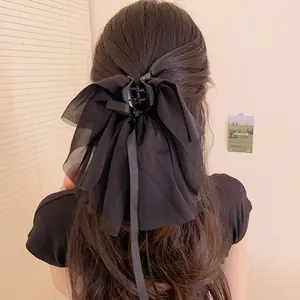 Eleganter schwarzer übergroßer Schleifen-Haarclip an braunem gewelltem Haar