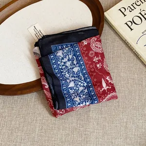 Detail of a vintage floral print bandana folded on a rustic wooden tray and book.