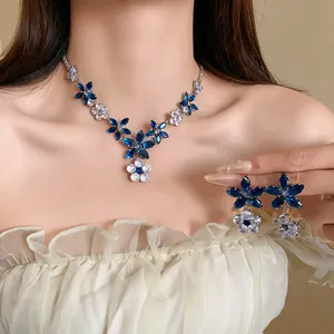 Primo piano di un elegante set di collana e orecchini con fiori in zircone blu su modella