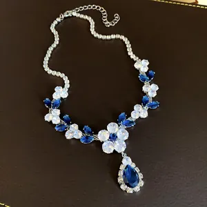 Dettaglio macro di una collana a fiori in zircone con un grande pendente a goccia blu