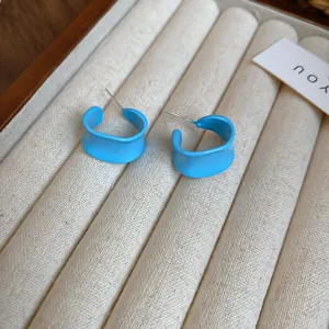 Primo piano di orecchini a cerchio blu ondulati a forma di C su vassoio in velluto