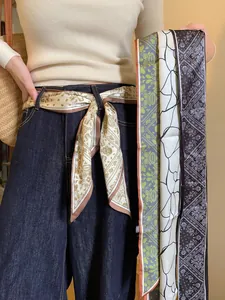 Multi-patterned paisley and floral scarves styled as a belt on denim pants for women