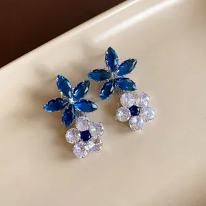 Primo piano di orecchini pendenti a fiore in zircone blu zaffiro e trasparente per gala