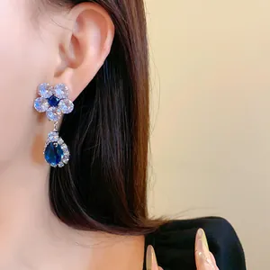 Dettaglio degli eleganti orecchini a goccia con fiori di zircone blu e bianco