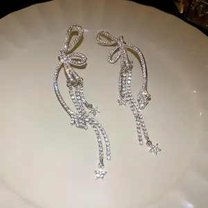 Elegante silberne Schleifen-Ohrringe mit glitzernden Strasssteinen und Sternen.