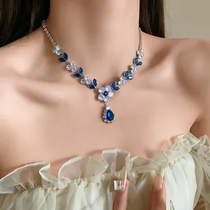 Primo piano di una collana in zircone con fiori, foglie e pendente a goccia blu