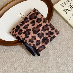Detail view of a retro leopard print fabric headscarf on a stylish wooden tray.