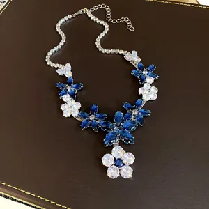 Primo piano di una collana elegante con fiori e foglie in zirconi blu e trasparenti