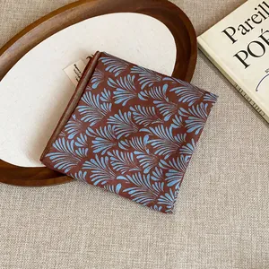 Close-up of retro brown bandana with blue palm leaf pattern on textured background