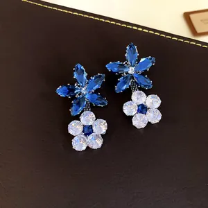 Primo piano di eleganti orecchini a doppio fiore con zirconi blu e trasparenti