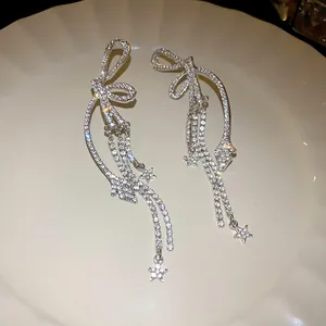 Funkelnde silberne Schleifen-Ohrringe mit Strass-Tasseln und Sternen-Anhängern Detail