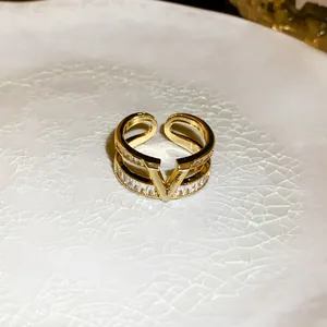 Detailed view of a gold-plated double-layer ring featuring a central V-logo and zircons.