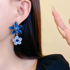 Primo piano di eleganti orecchini a fiore in zircone blu indossati da una modella di classe.