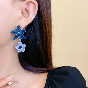 Dettaglio ravvicinato di eleganti orecchini a fiore in zircone blu e bianco su modella