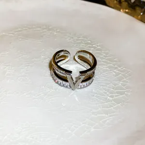 Macro view of double-layered silver ring with V-shape logo and cubic zirconia detail