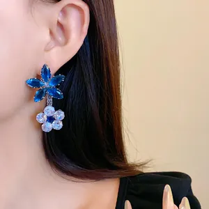 Dettaglio ravvicinato di eleganti orecchini a fiore in zircone blu su una modella asiatica