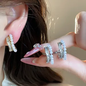 Detailed view of 18k gold plated pearl and baguette-cut cubic zirconia ear clips