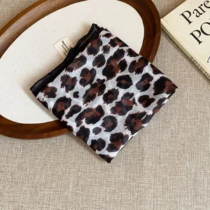 Close-up detail of a retro leopard print fabric bandana folded on a rustic wooden tray
