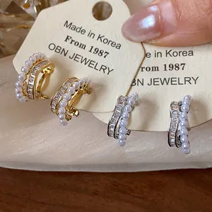 Close-up of 18k gold plated earrings with zirconia and pearls on display card