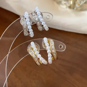 Macro detail of French style 18k gold plated pearl and baguette zircon earrings set on display
