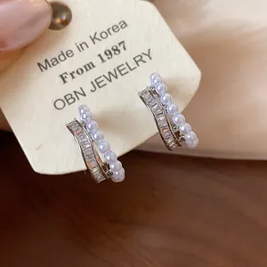 Close-up of elegant double-row clip earrings with pearls and baguette-cut zircons