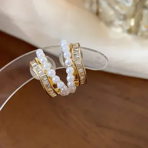 Macro detail of French style 18k gold plated earrings with pearls and baguette zircon
